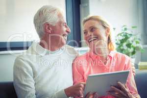 Senior couple smiling while using digital tablet