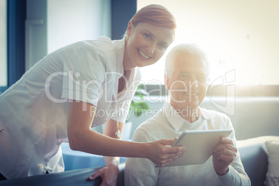 Female nurse showing medical report to senior man on digital tablet