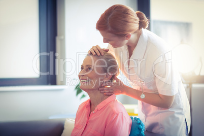 Female nurse giving head massage to woman