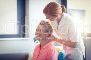 Female nurse giving head massage to woman