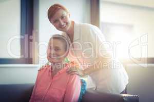 Portrait of happy nurse and patient in living room