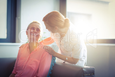 Happy nurse and patient in living room