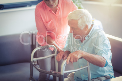Senior woman helping senior man to walk with walker