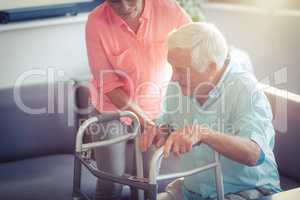 Senior woman helping senior man to walk with walker