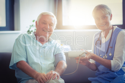 Female doctor checking blood pressure of senior man