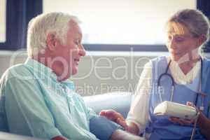 Female doctor checking blood pressure of senior man