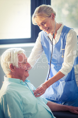 Female doctor checking heartbeat of senior man
