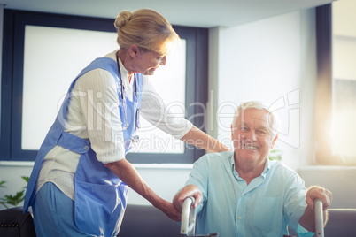 Female doctor helping senior man to walk with walker