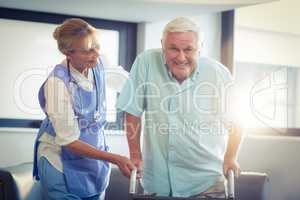 Female doctor helping senior man to walk with walker