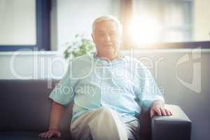 Portrait of happy senior man sitting on sofa