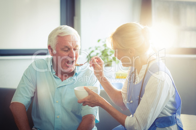 Female doctor feeding senior man