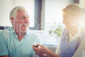 Female doctor giving medicine to senior man