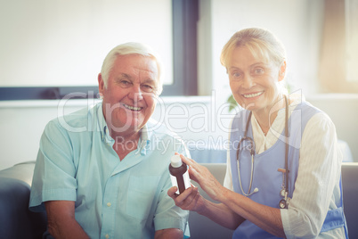 Female doctor giving medicine to senior man