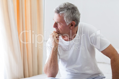 Worried senior man sitting on bed