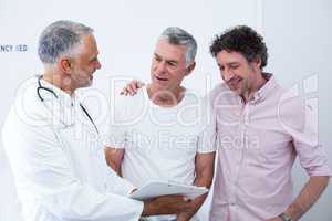 Senior man and his guardian talking to the doctor