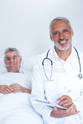 Male doctor writing medical report of senior man on clipboard