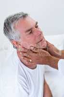 Male doctor examining senior mans neck