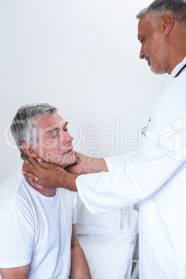 Male doctor examining senior mans neck