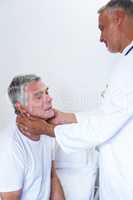 Male doctor examining senior mans neck