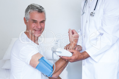 Doctor checking senior mans blood pressure