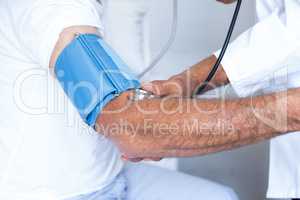 Doctor checking senior mans blood pressure