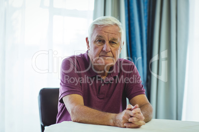 Worried senior man sitting beside table