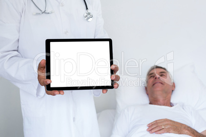 Doctor standing next to the patient and holding a digital tablet
