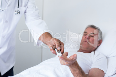Male doctor testing diabetes of senior man on glucose meter