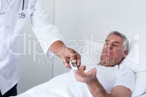 Male doctor testing diabetes of senior man on glucose meter