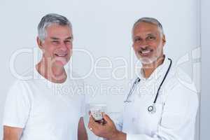 Portrait of male doctor giving pills to senior man