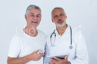 Male doctor showing medical reports to senior man on digital tablet