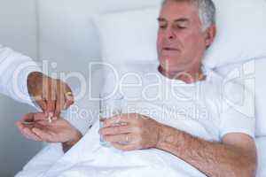 Male doctor giving pill to senior man