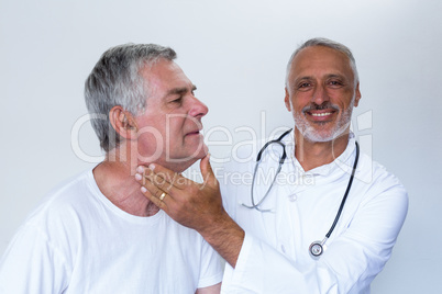 Male doctor examining senior mans neck