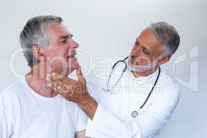 Male doctor examining senior mans neck
