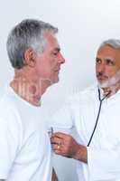 Male doctor checking heartbeat of senior man