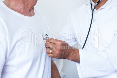 Male doctor checking heartbeat of senior man