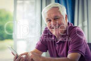 Portrait of senior man using mobile phone at home