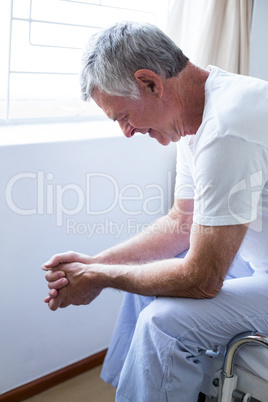 Upset senior man sitting on bed