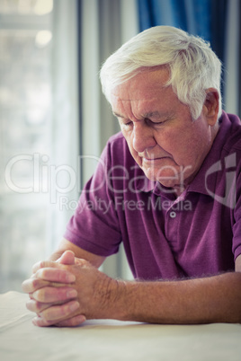 Senior man praying in living room