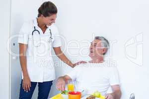 Female doctor talking to senior man while having breakfast