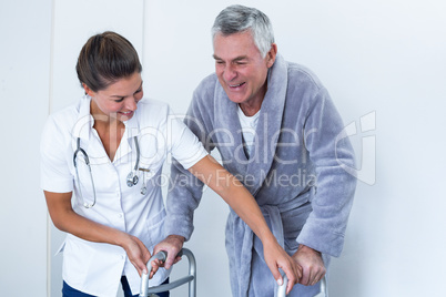 Female doctor helping senior man to walk with walker
