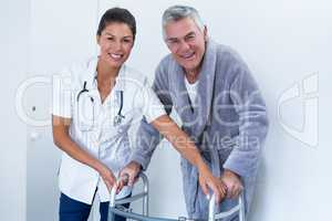 Portrait of female doctor helping senior man to walk with walker