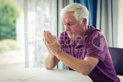 Senior man praying in living room