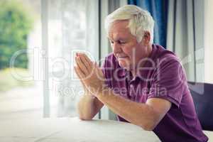 Senior man praying in living room