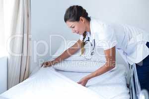 Smiling female doctor preparing the bed