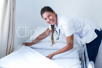 Portrait of smiling female doctor preparing the bed