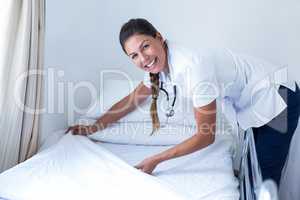 Portrait of smiling female doctor preparing the bed