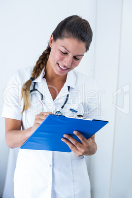 Female doctor writing on clipboard in hospital