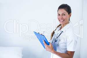 Portrait of female doctor writing on clipboard in hospital