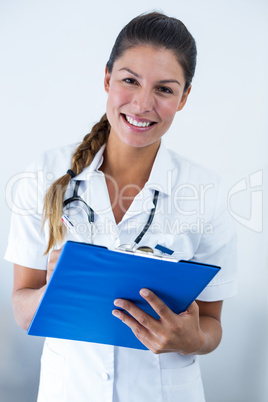 Portrait of female doctor writing on clipboard in hospital